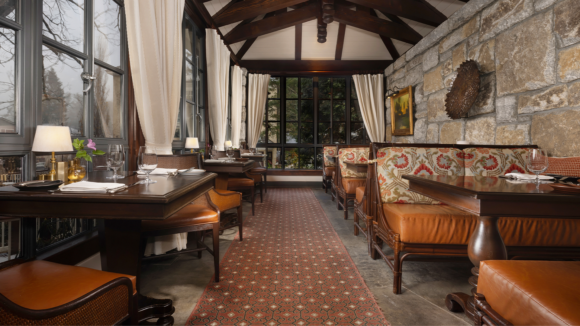 a room with a stone wall and tables and chairs