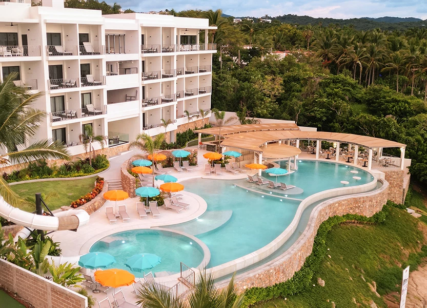 a pool with umbrellas and chairs in front of a building
