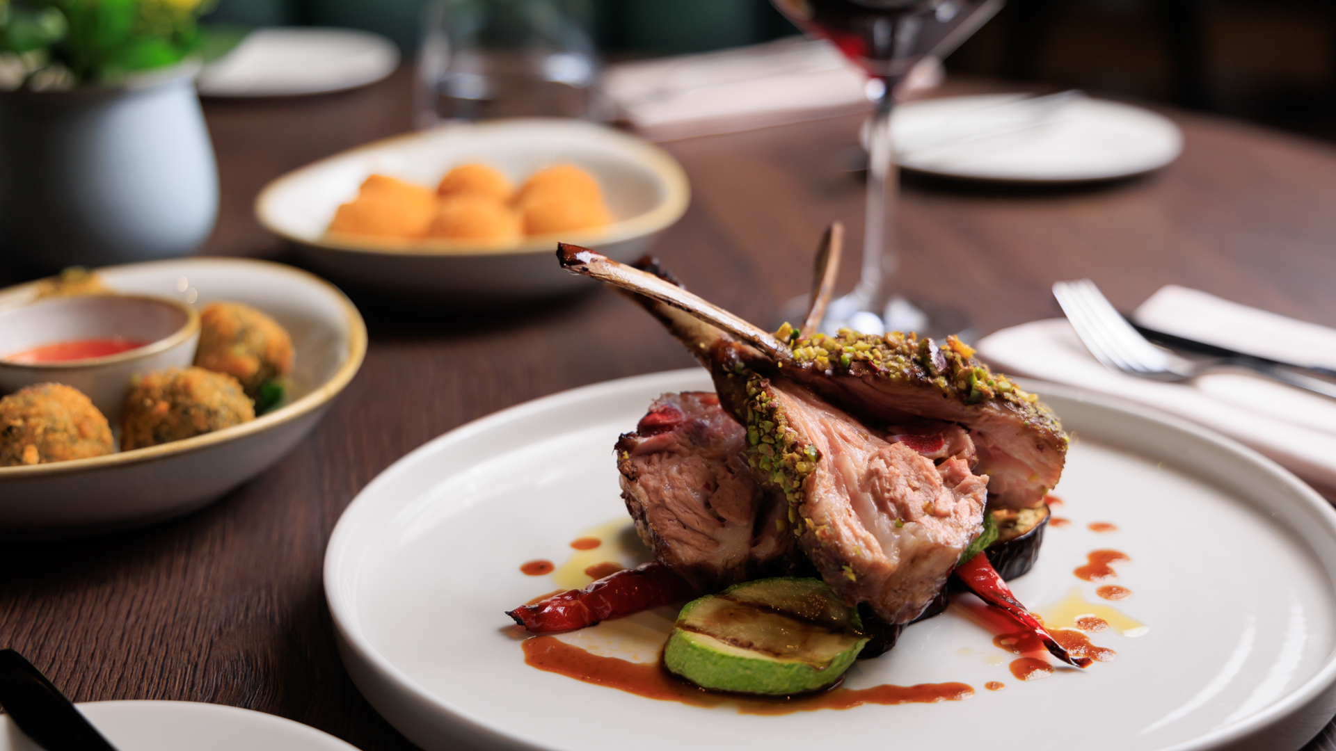 Plated lamb chops with vegetables and sauce in a restaurant setting