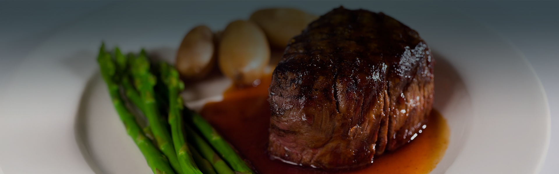 a piece of steak with asparagus and potatoes