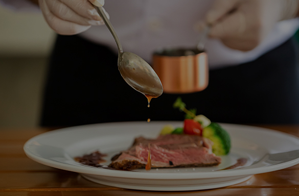 a person pouring sauce over a plate of food