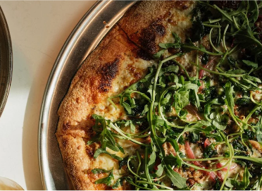 a pizza with green leaves on it