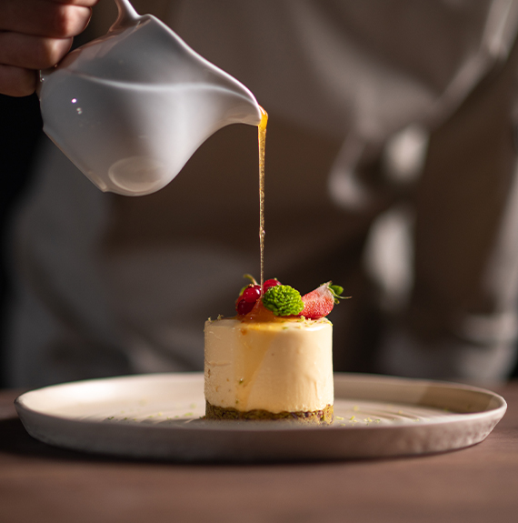 a person pouring liquid onto a dessert