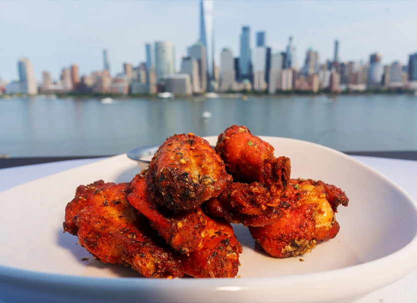 a plate of chicken wings with a city in the background