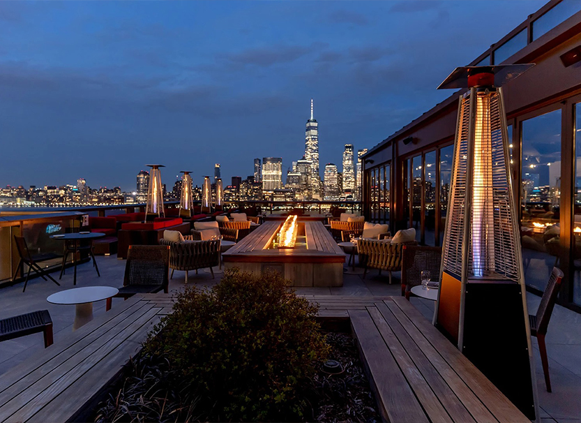 a rooftop patio with a fire pit and a city skyline in the background