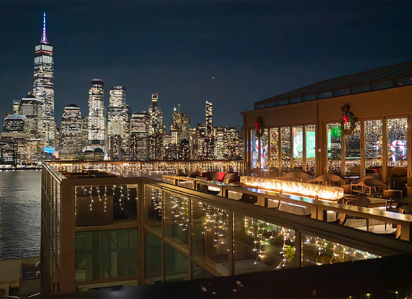 a rooftop bar with lights and city skyline in the background