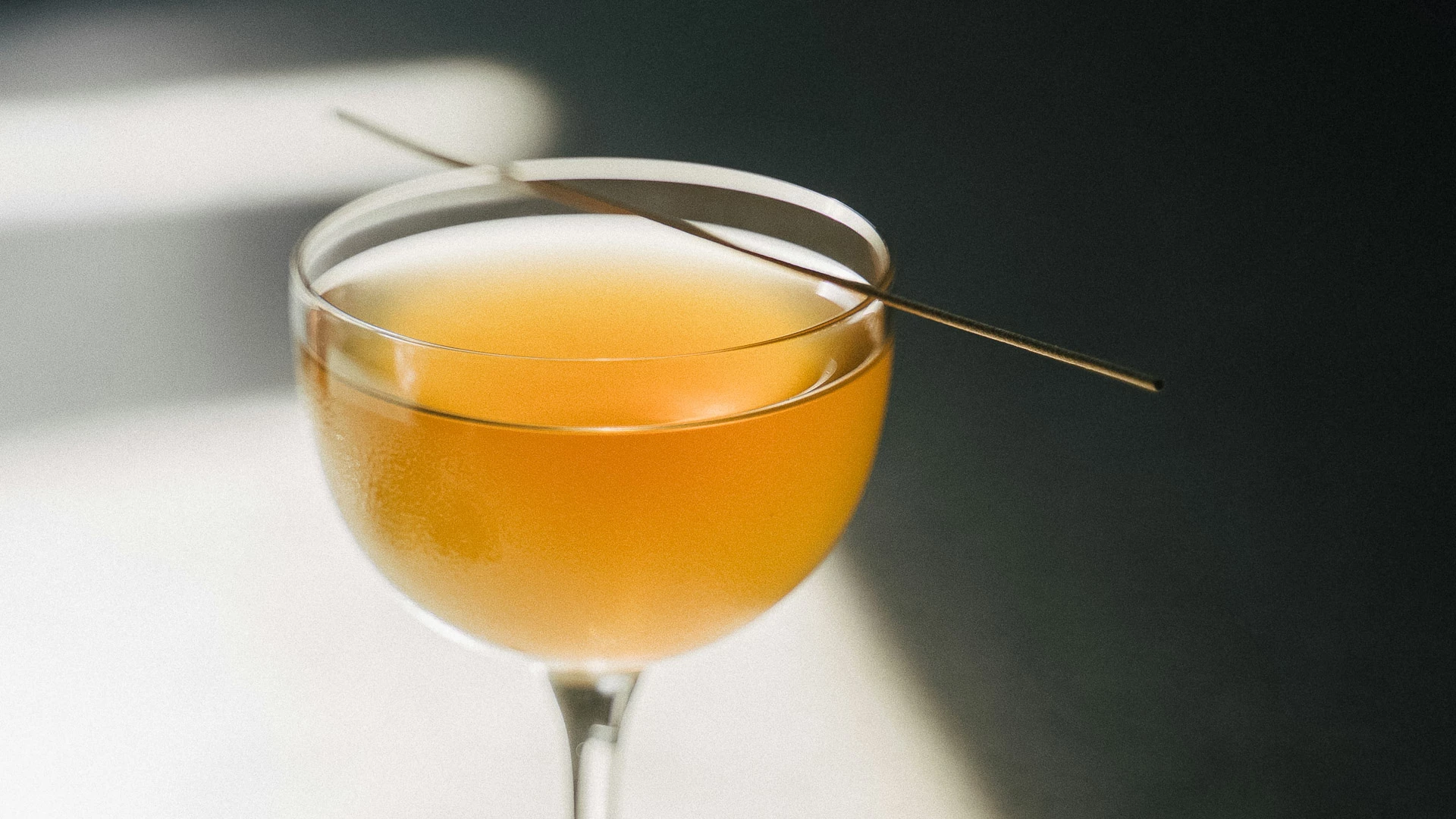 a glass of liquid with a toothpick in it