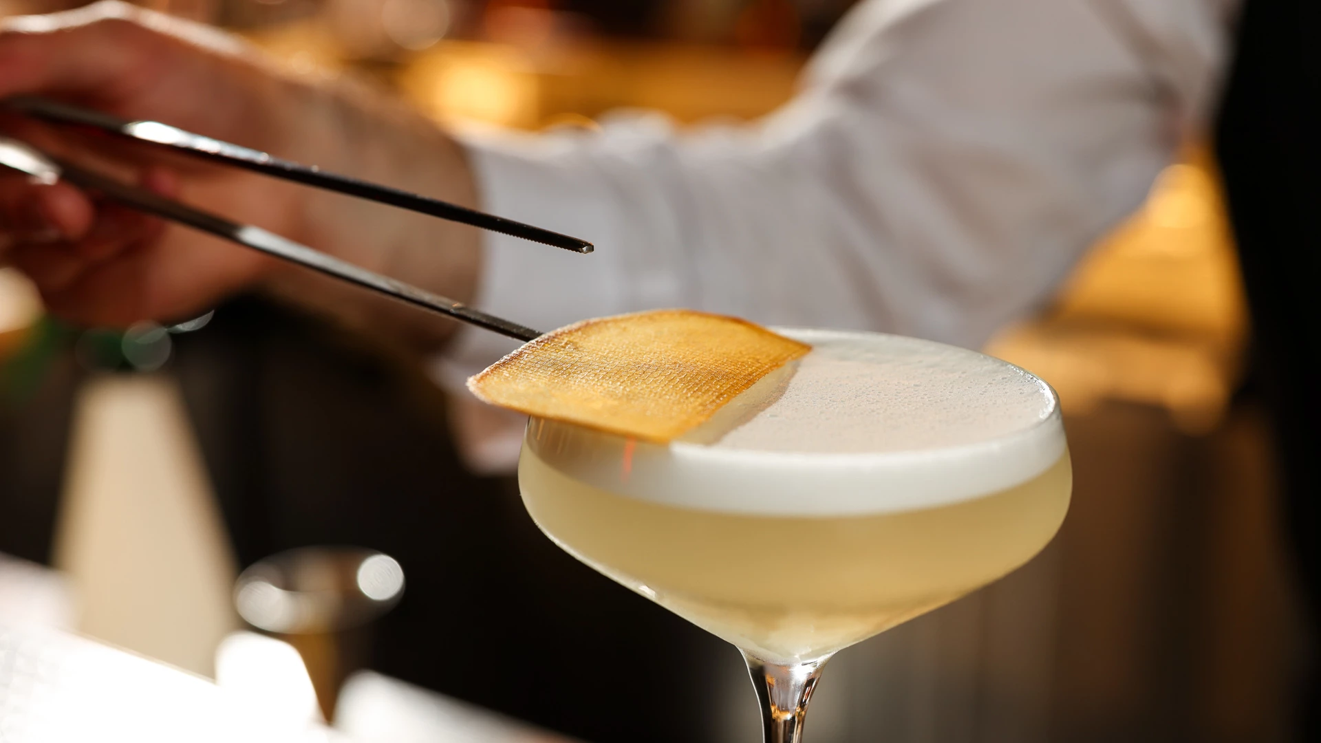 a person holding a drink with tongs