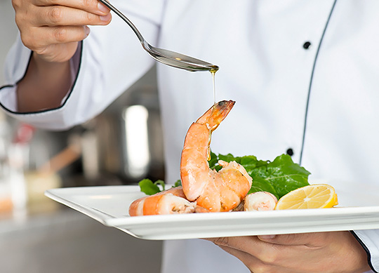 a person pouring oil onto a plate of shrimp