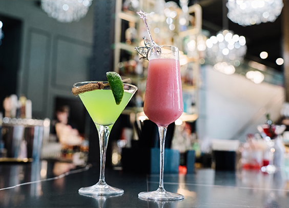 two glasses of drinks on a bar