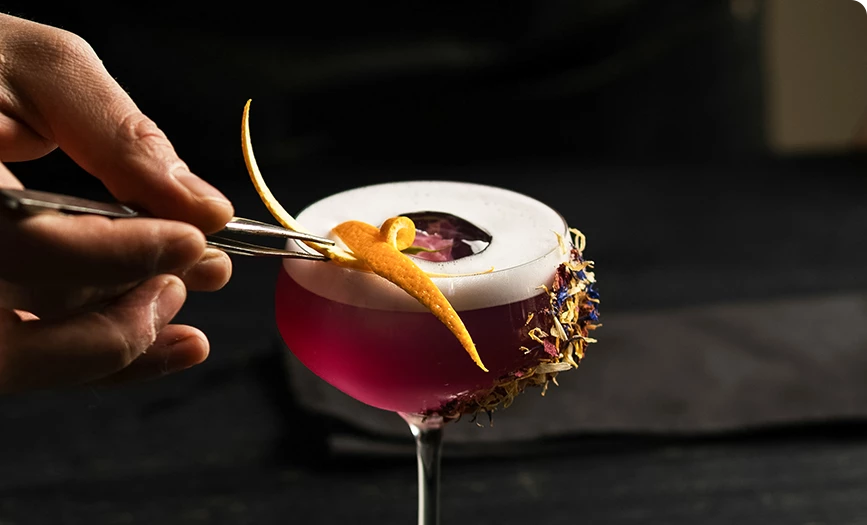 a hand holding a tweezers with a drink