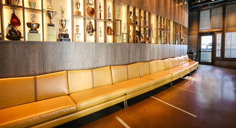 a row of long leather seats in a room with trophies on the wall