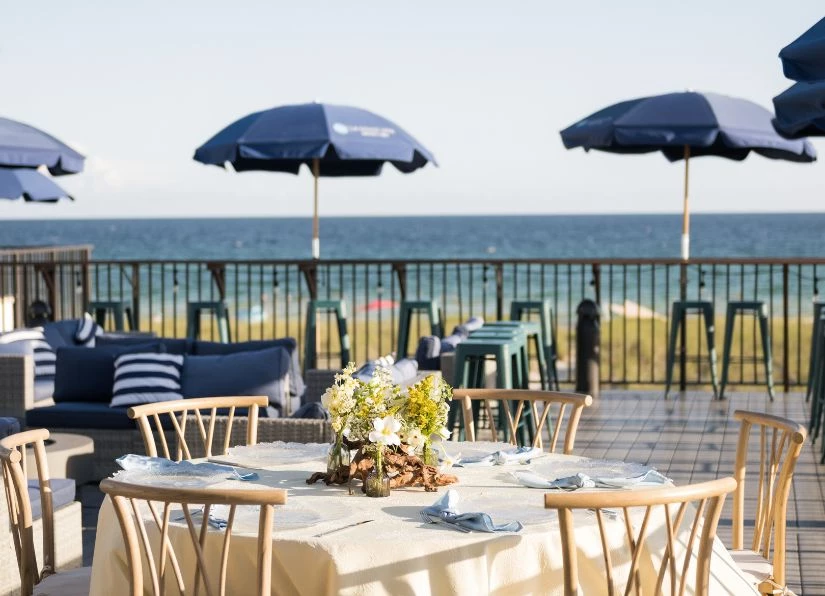 a table set up with chairs and umbrellas on a patio