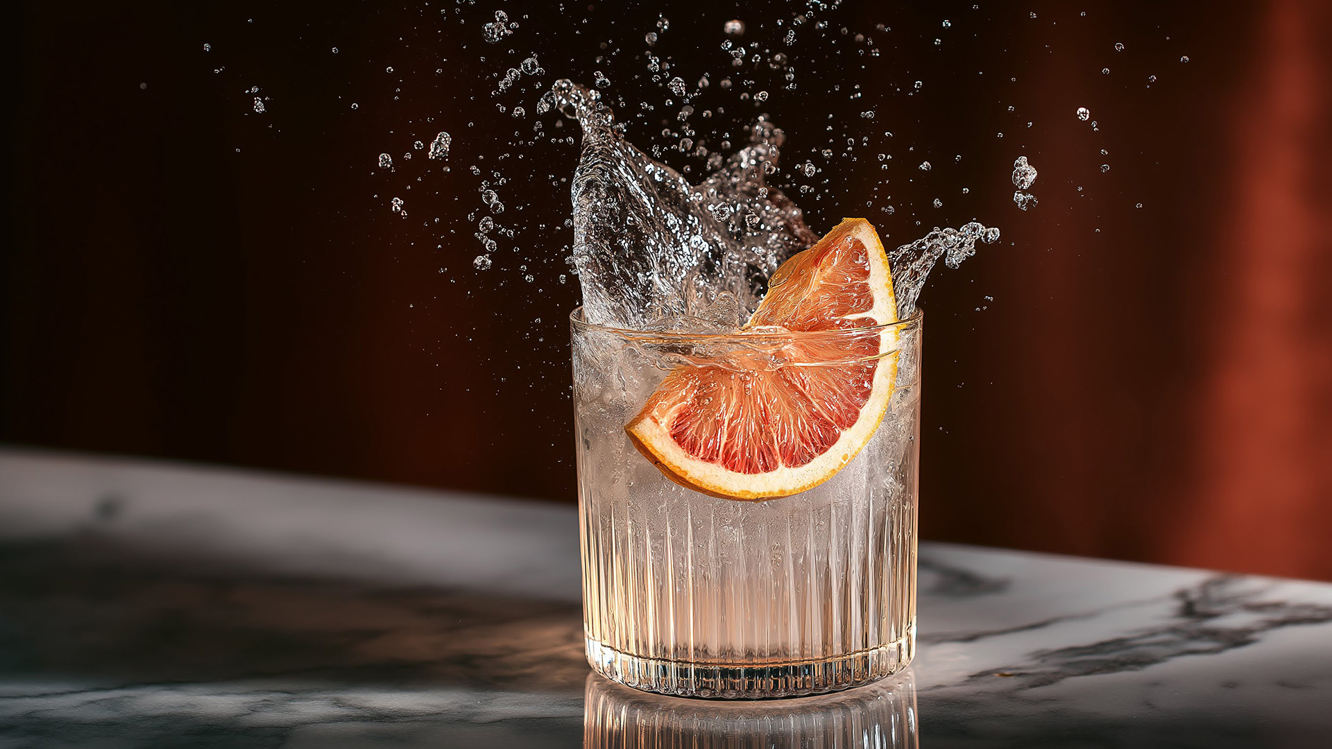 a glass of water with an orange slice and ice
