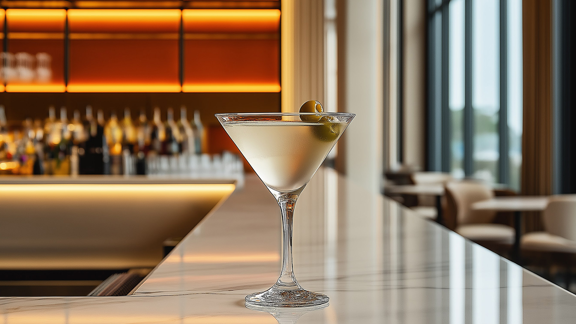 a martini glass with a green olive on top