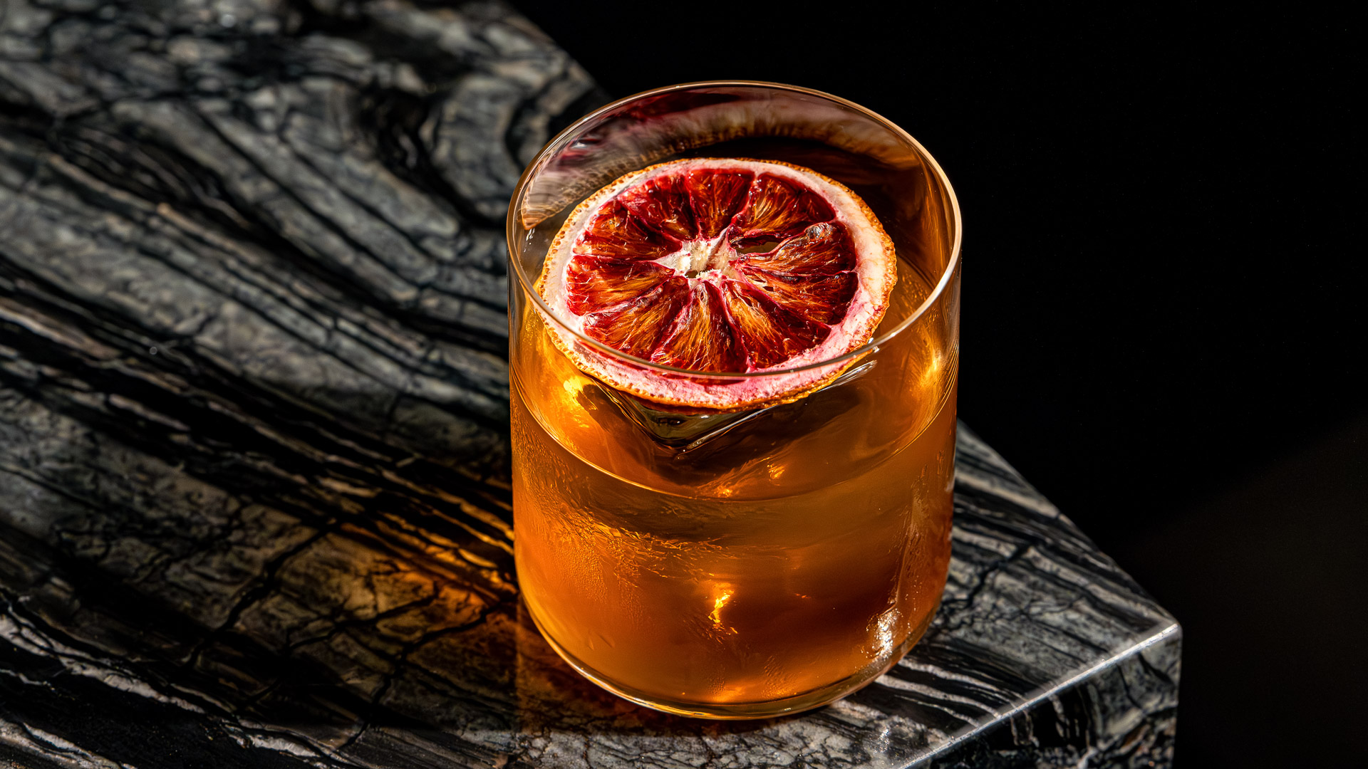 a glass of liquid with a slice of orange on top