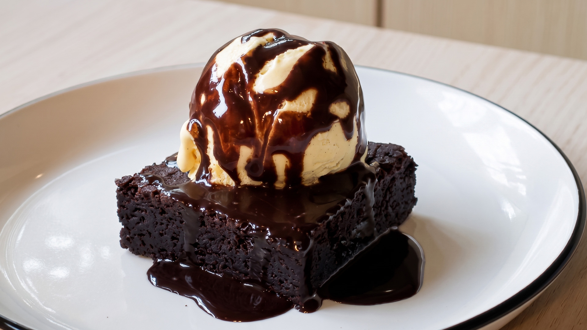 a brownie with ice cream and chocolate sauce on a white plate