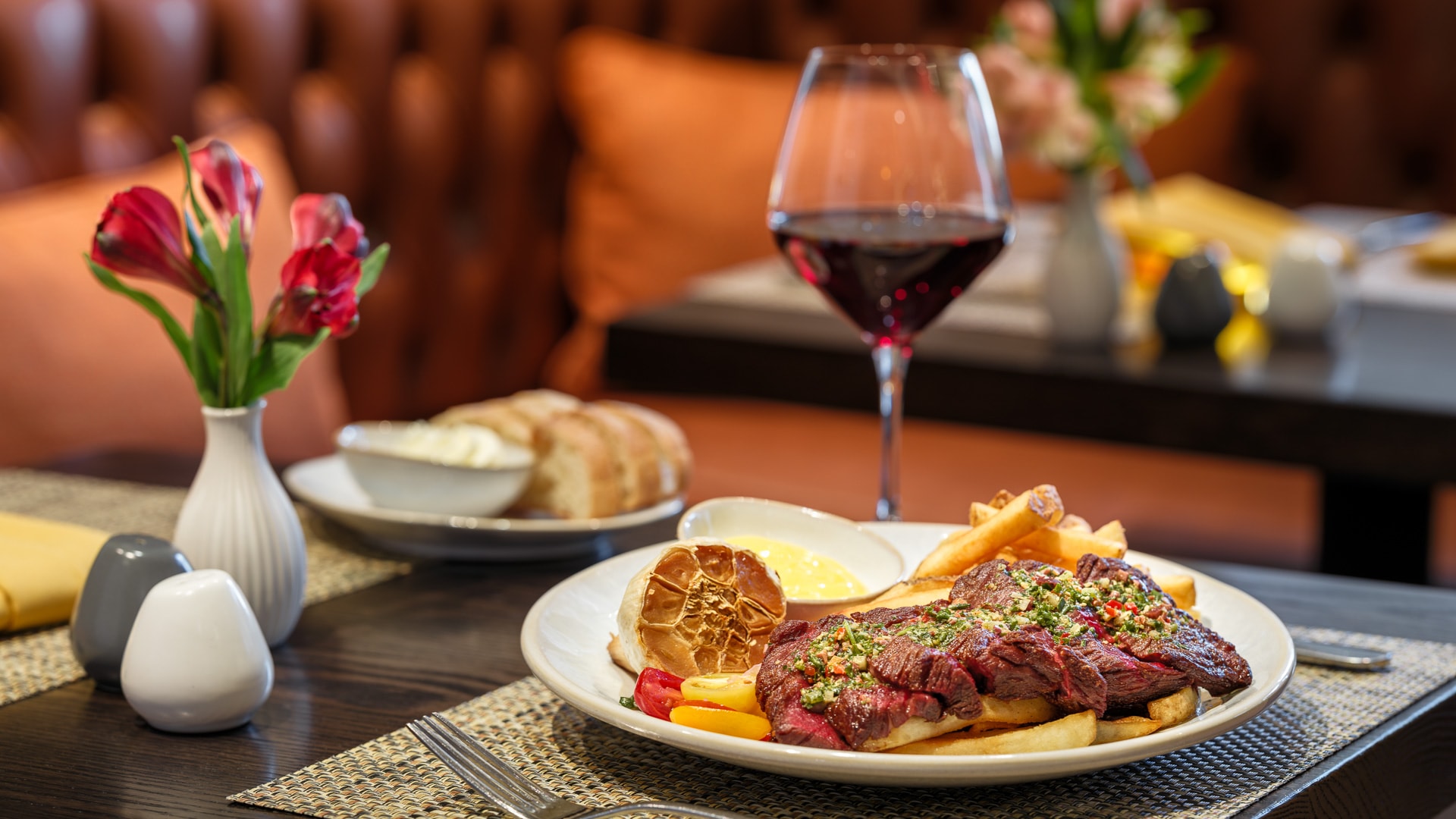 a plate of steak and french fries with a glass of wine