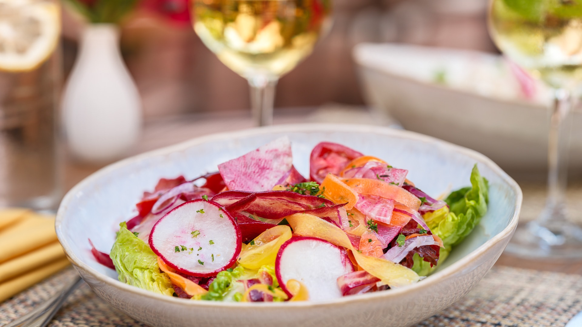 a bowl of salad with a glass of wine