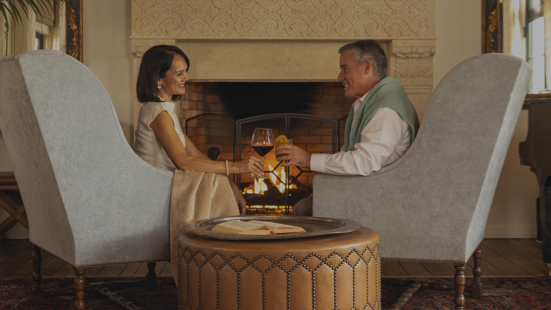a man and woman sitting in chairs holding wine glasses
