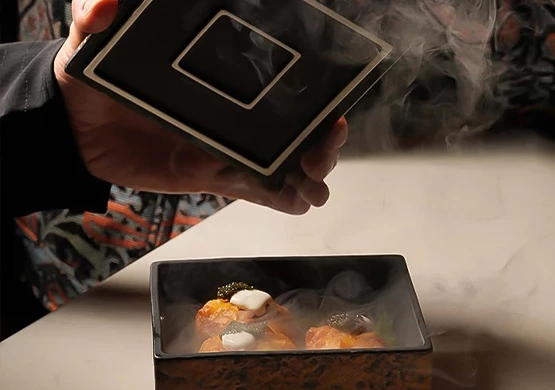 a person holding a square black box with food in it