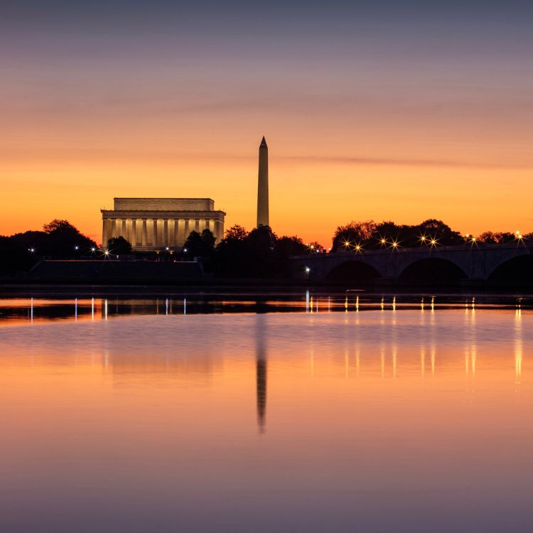 a body of water with a monument and a bridge in the background