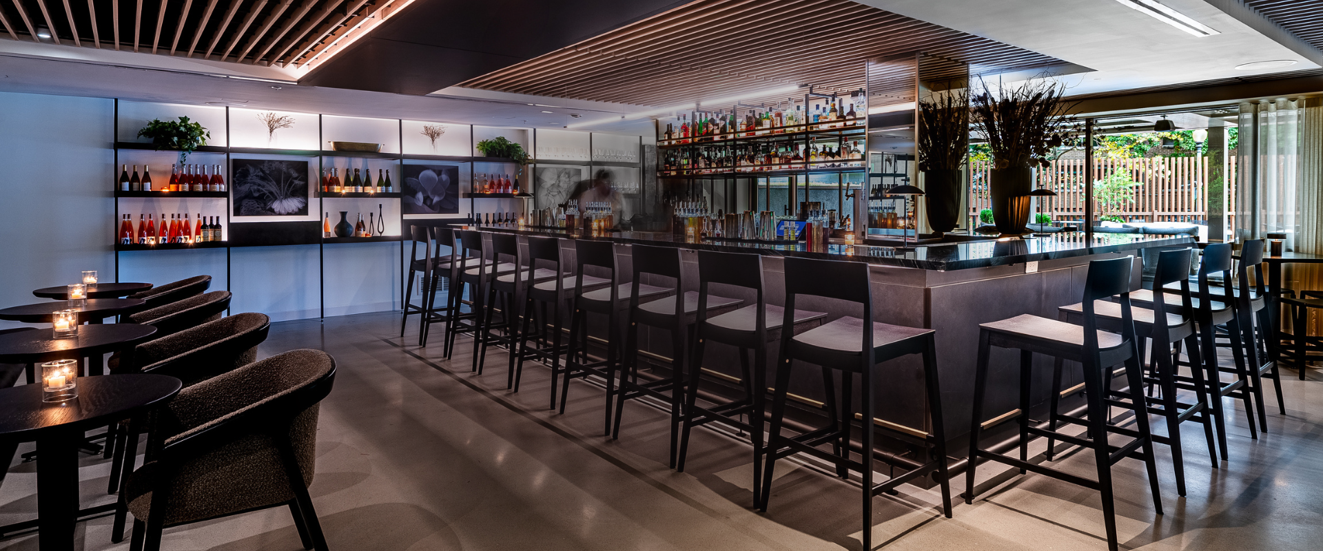 a bar with a row of chairs and bottles
