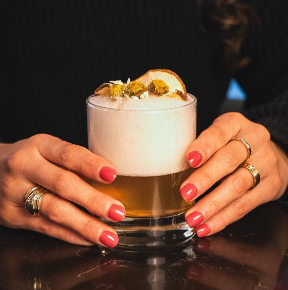 a woman holding a glass of liquid