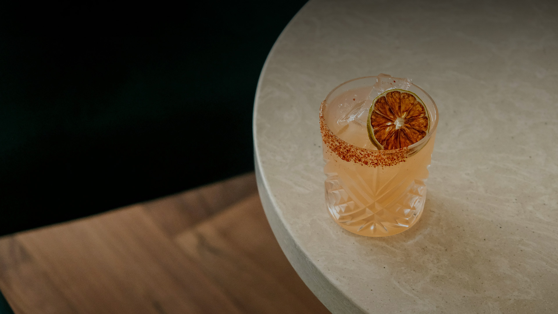 a glass of drink with a slice of lime and a slice of lime on a table
