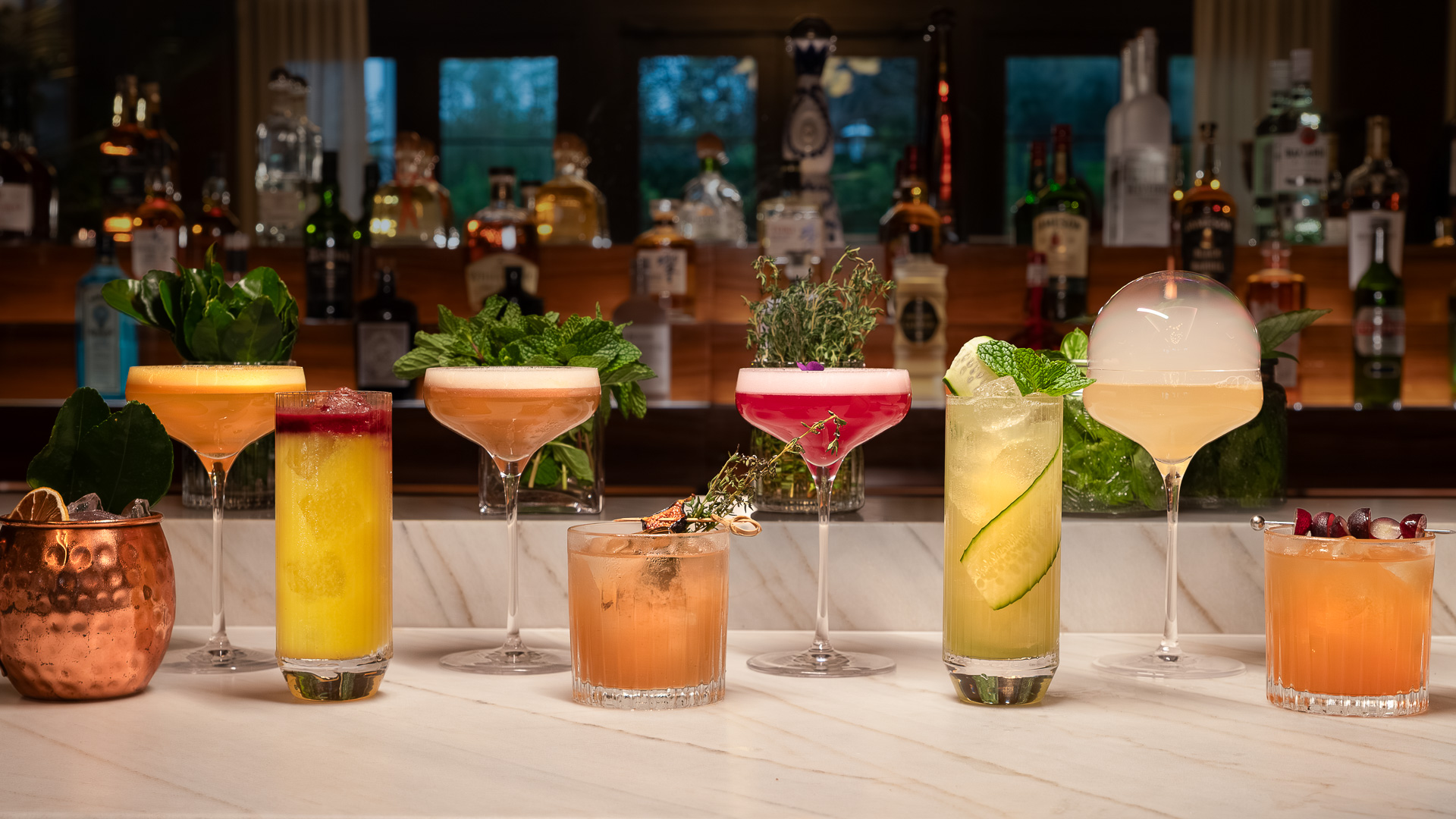 a row of different colored drinks on a counter