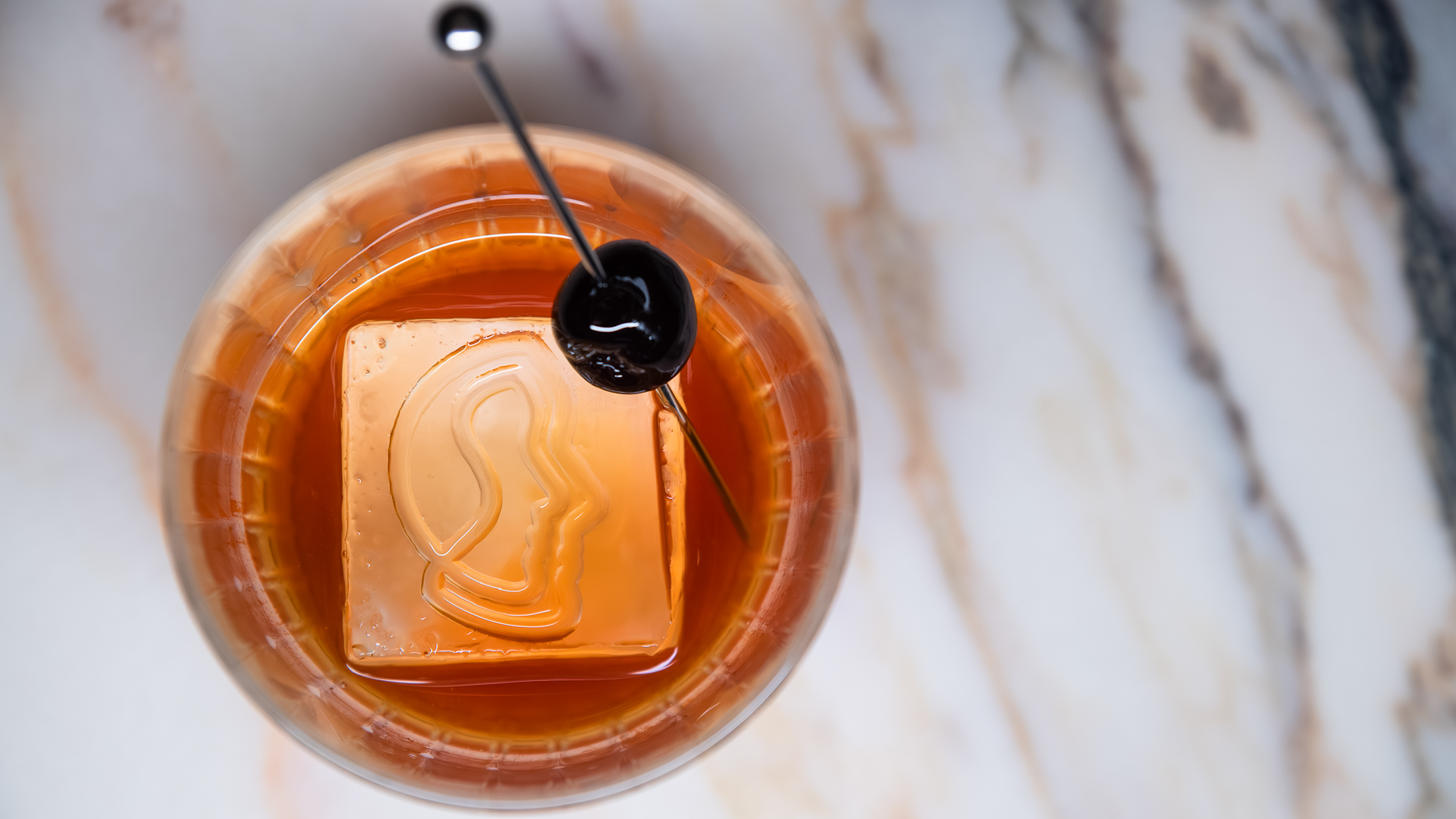 a glass with a drink and a cherry on it