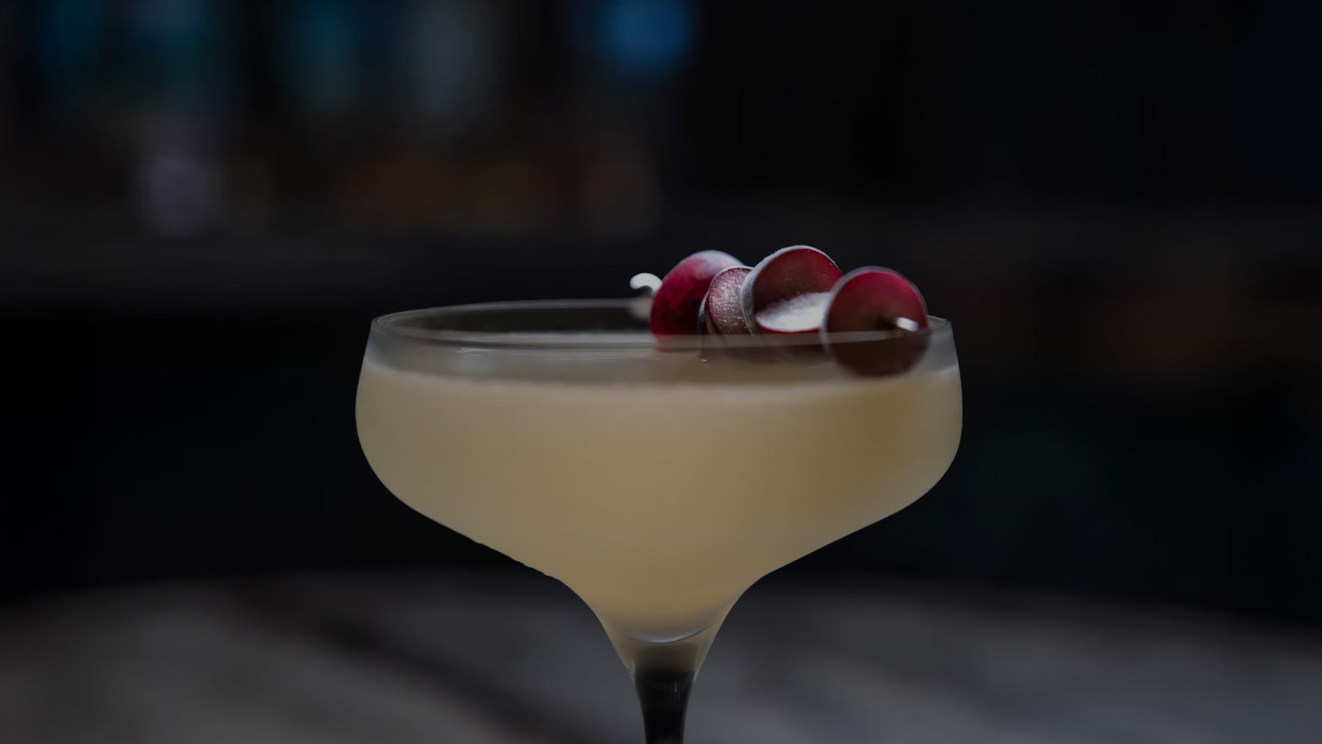 a glass with a drink and grapes on it