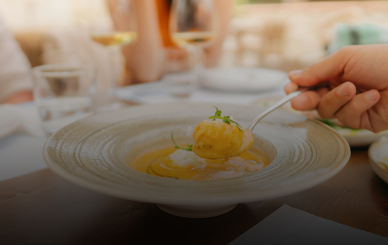 a person holding a spoon over a bowl of soup