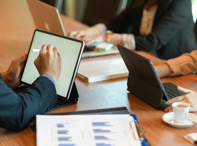 a group of people sitting at a table using devices