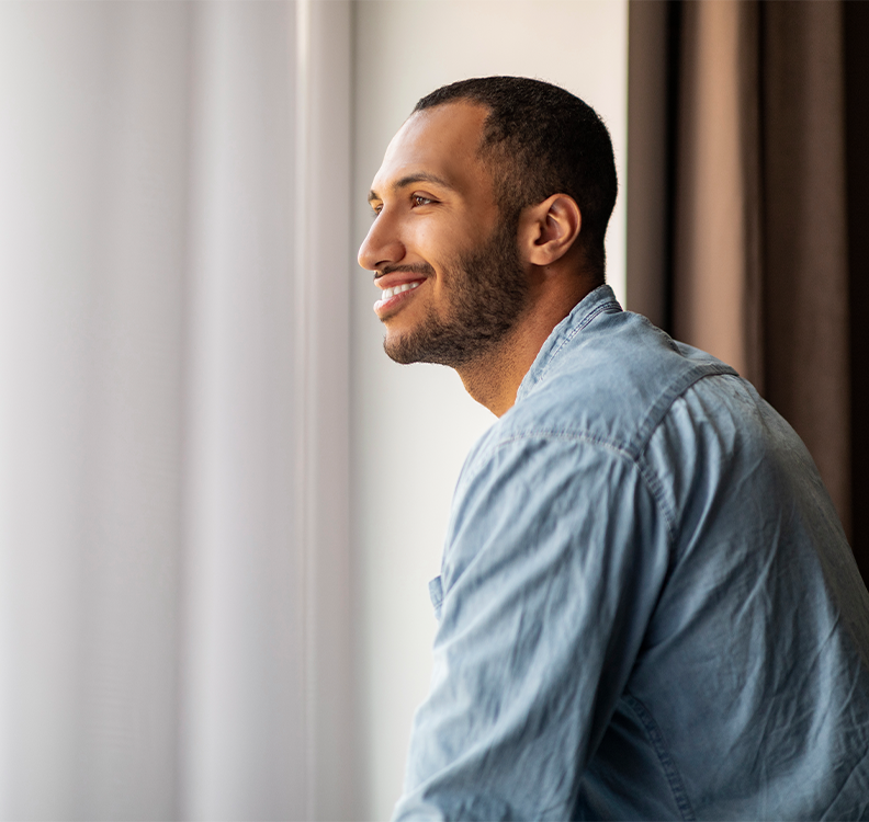 a man smiling and looking out a window