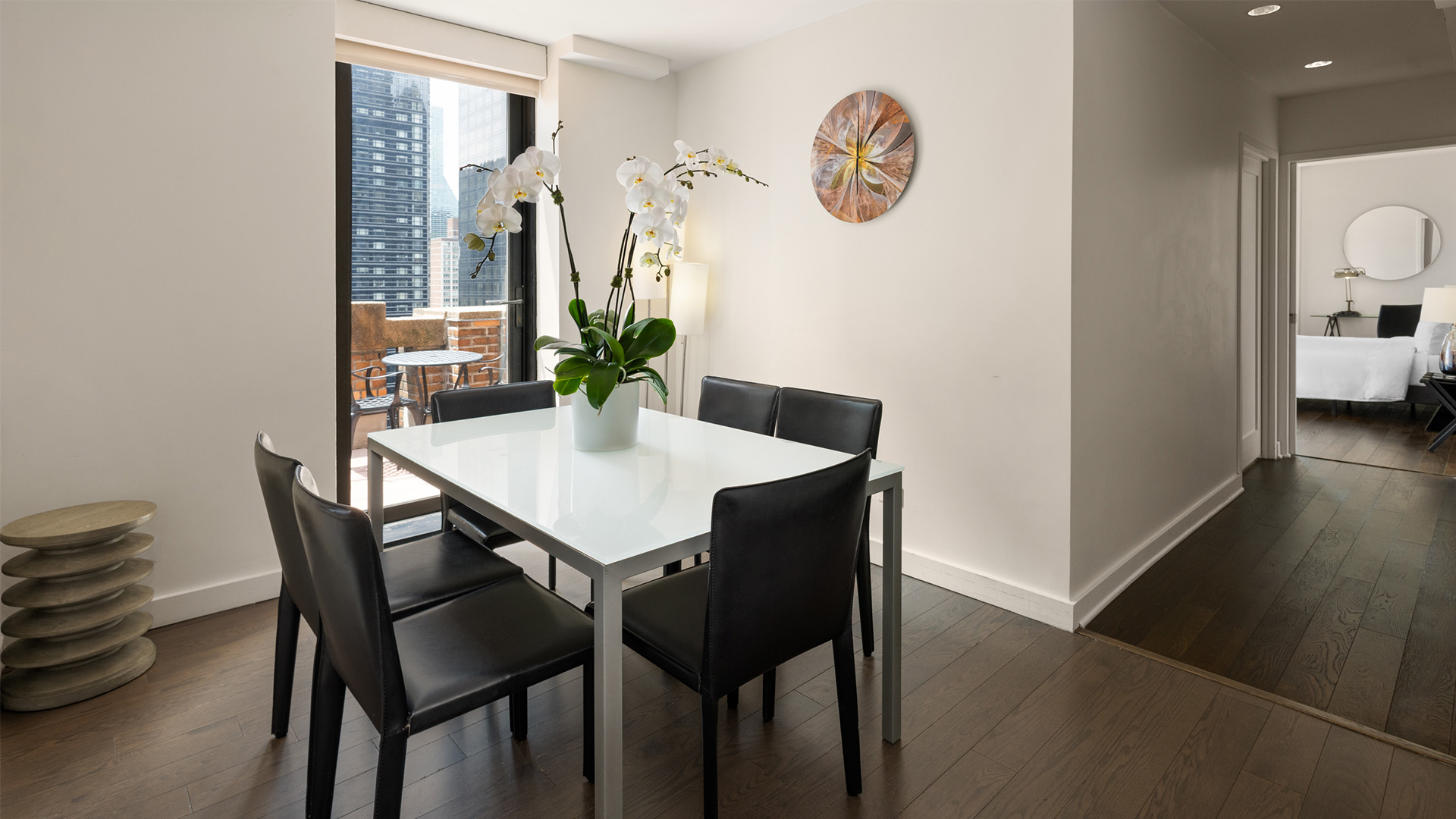 a white table with black chairs and a vase of flowers