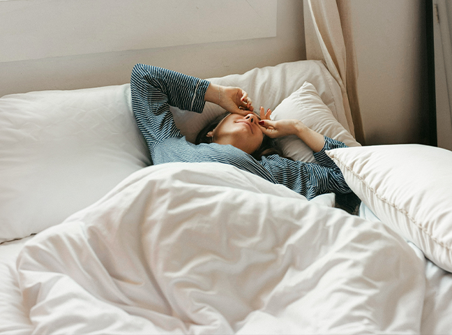 a woman lying in bed with her hands on her face
