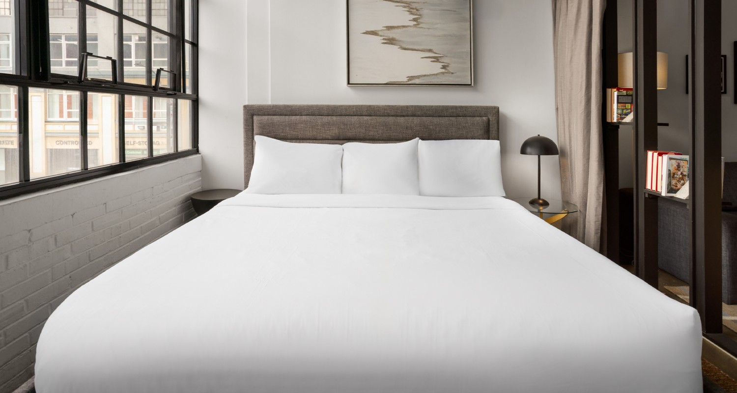 a bed with white sheets and a lamp