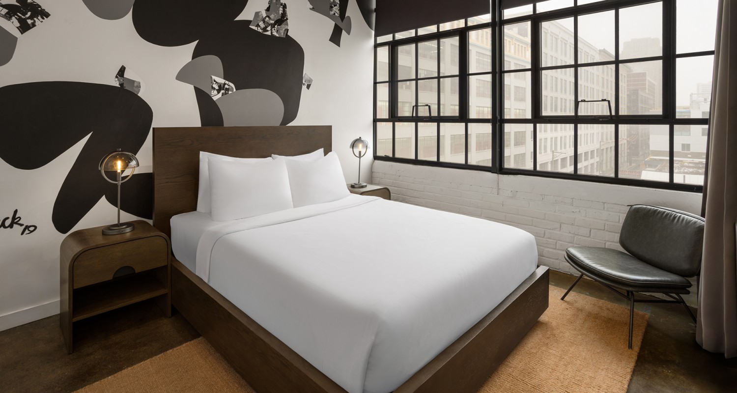a bed with white sheets and a lamp next to a window
