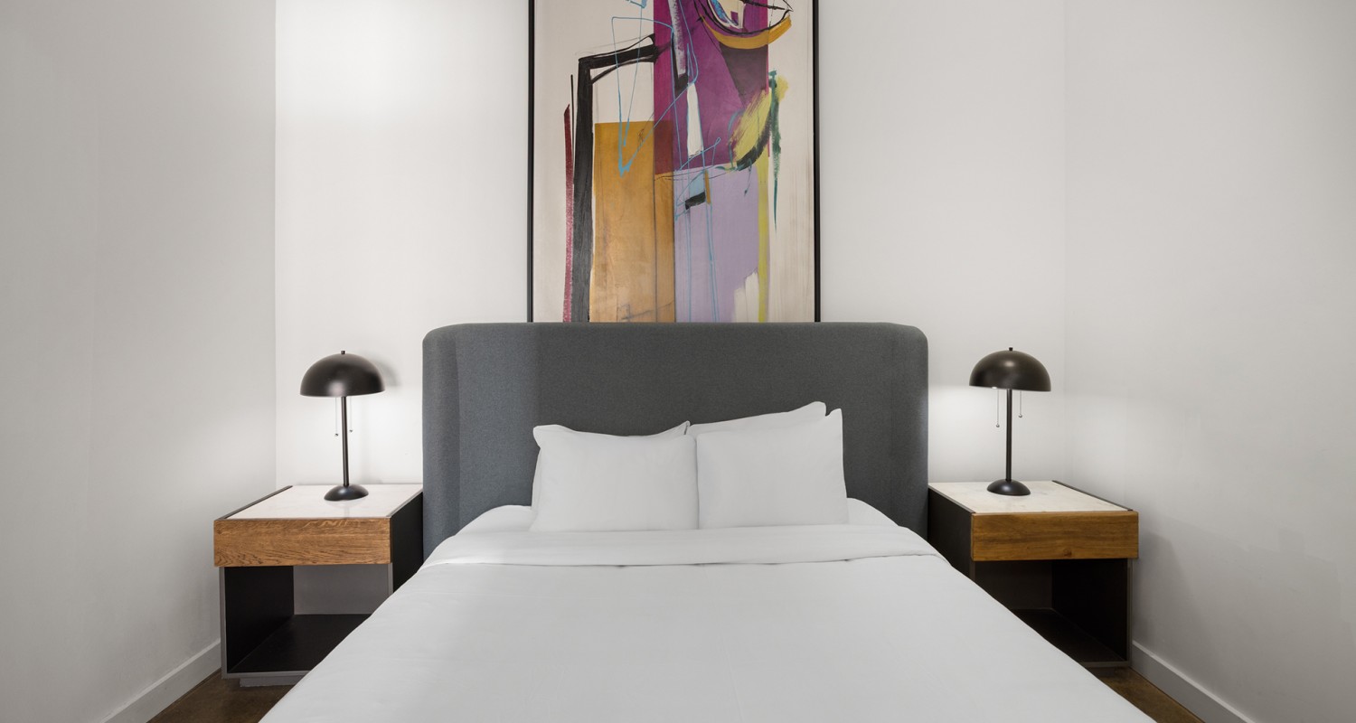 a bed with a painting above it