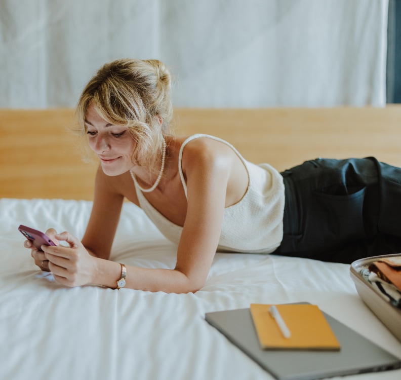 a woman lying on a bed looking at a phone