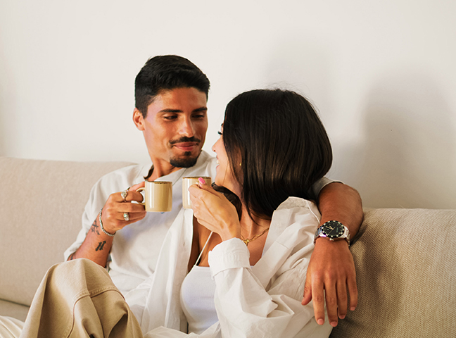 a man and woman sitting on a couch holding coffee cups