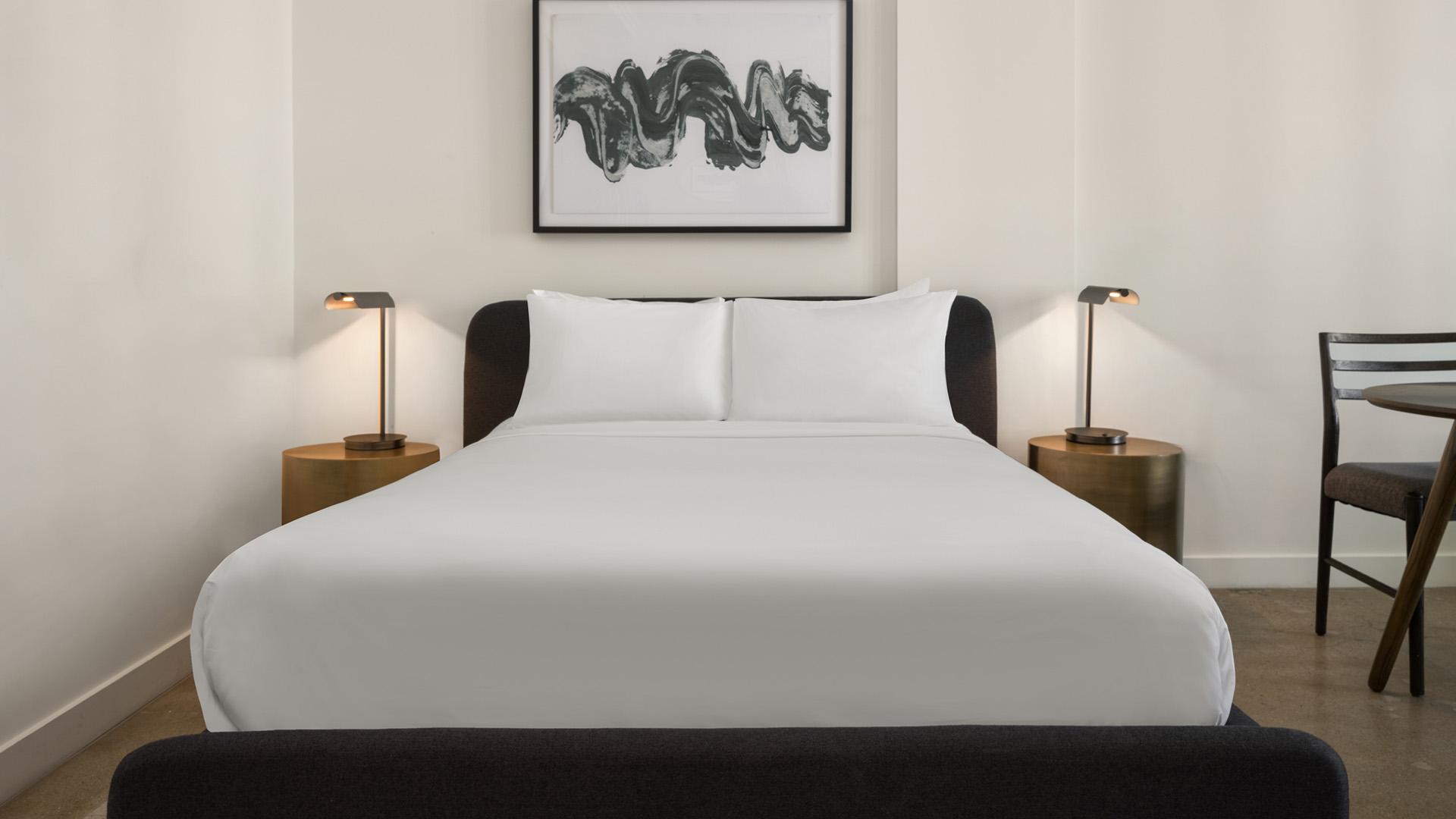 a bed with white sheets and two lamps