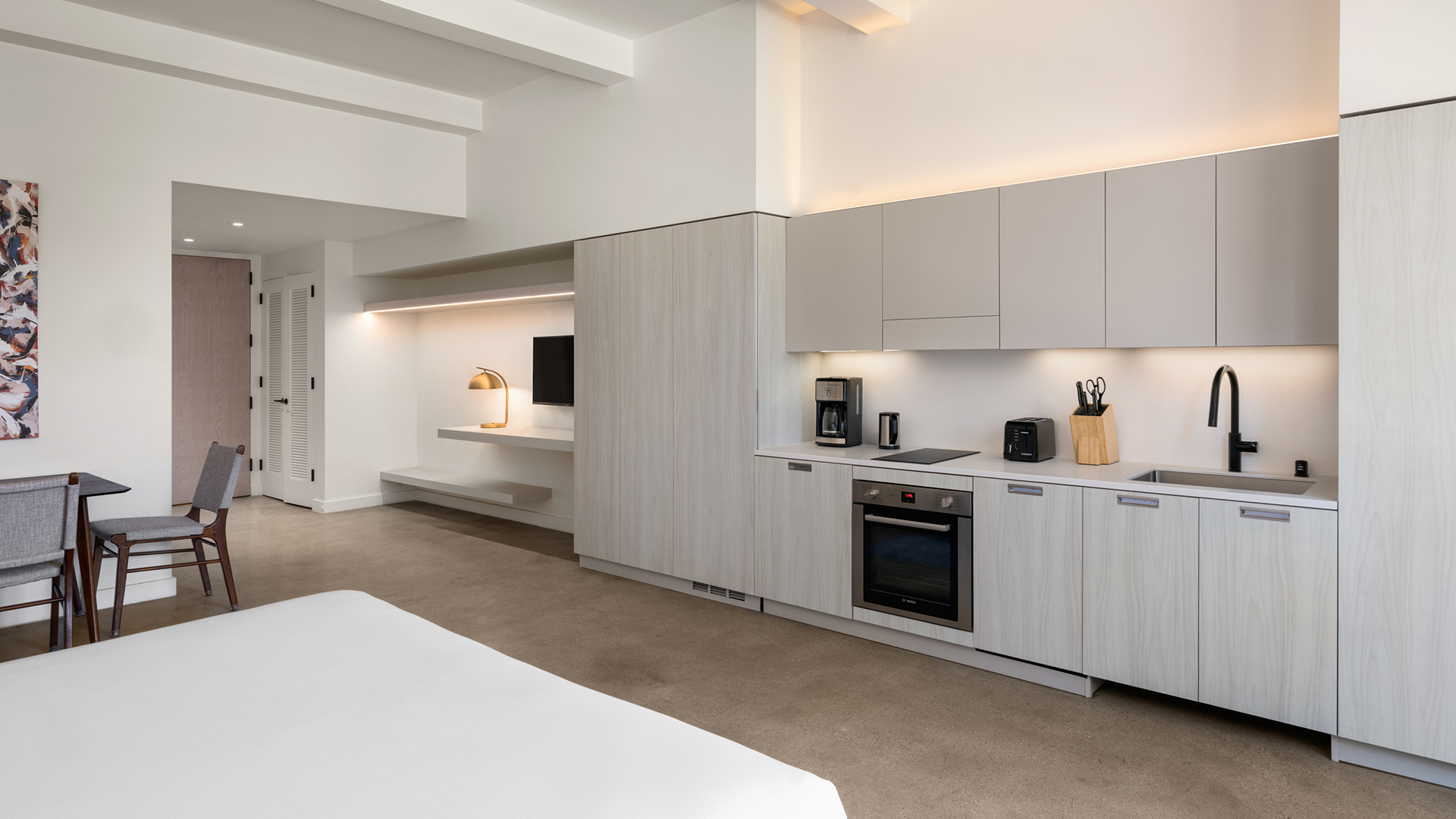 a kitchen with white cabinets and a bed