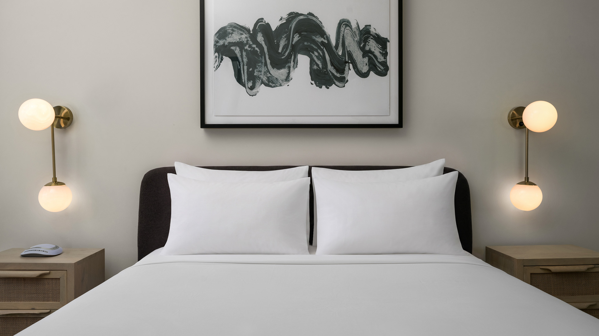 a bed with white sheets and a painting above it