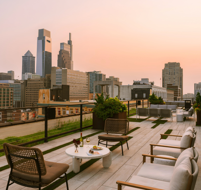 a rooftop patio with chairs and a table and a city skyline