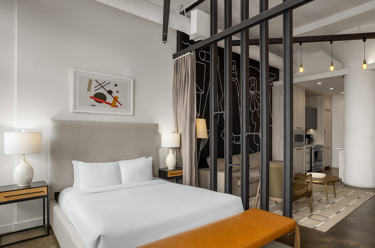 a bed with a bench in a room with a wall behind it
