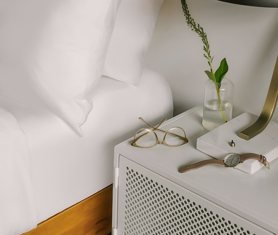 a white nightstand next to a bed