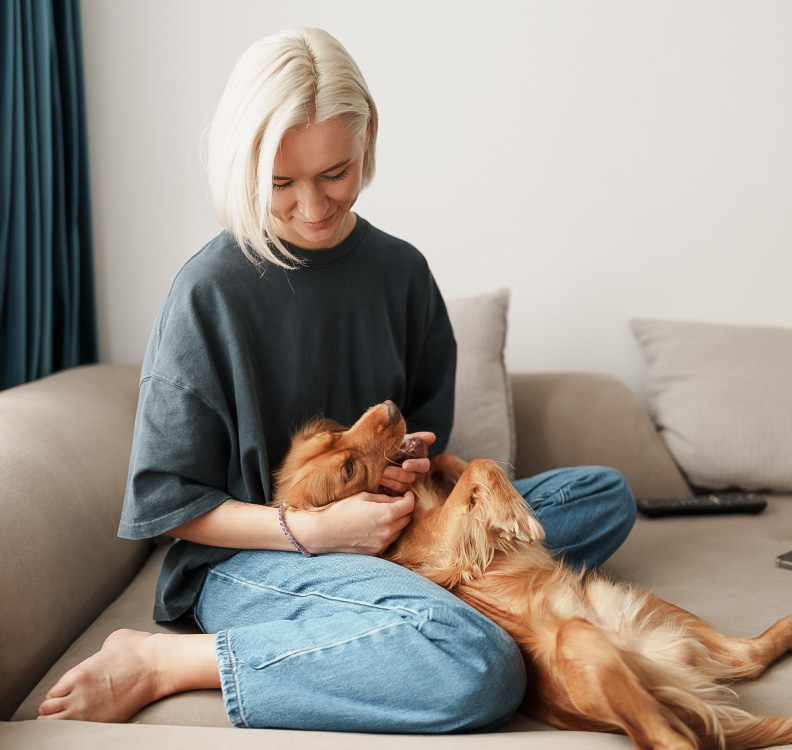 a woman sitting on a couch petting a dog