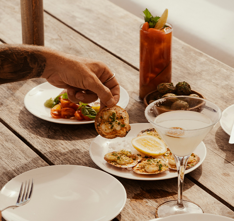 a person holding food on plates with a drink on it